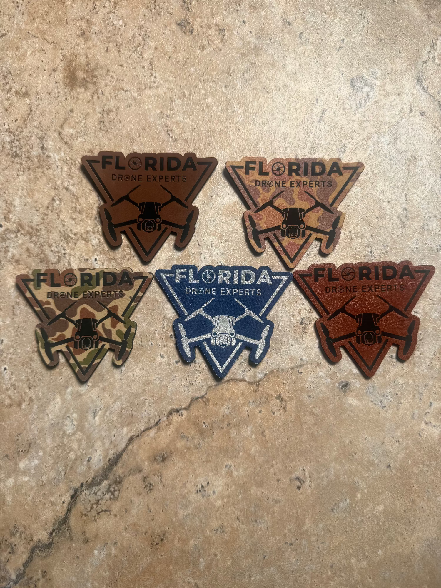 Five triangular patches with 'Florida Drone Experts' branding on a textured beige surface.