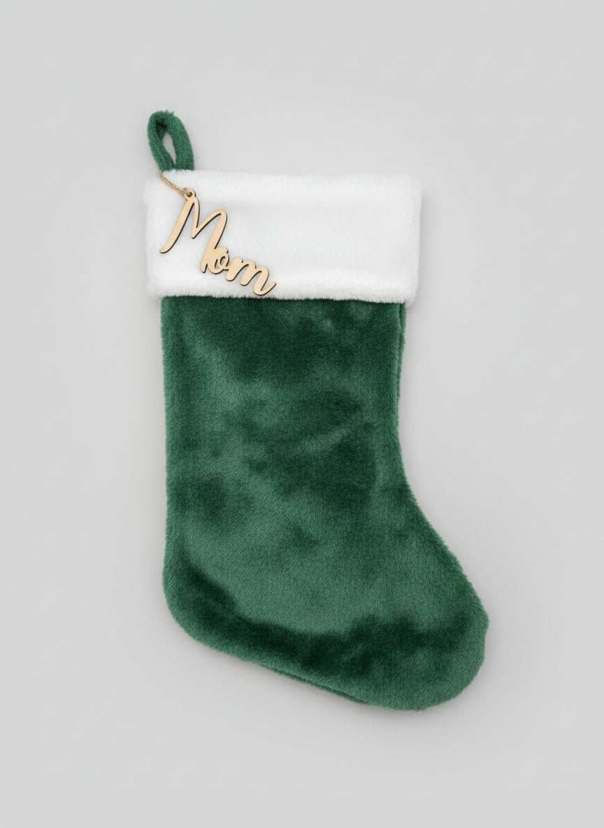 Green Christmas stocking with 'Mom' tag on a wooden surface