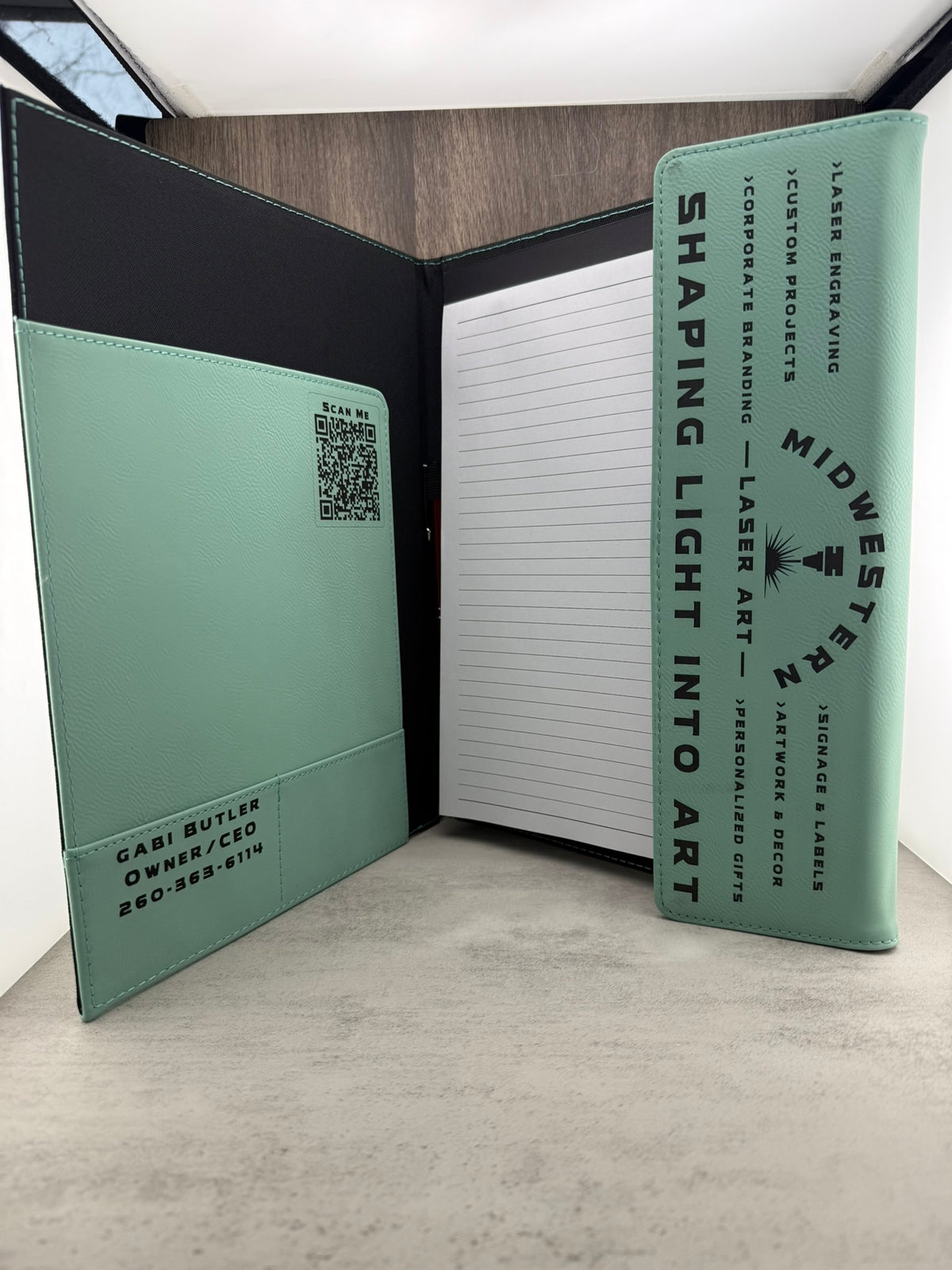 Green notebook with laser engraving on a gray surface