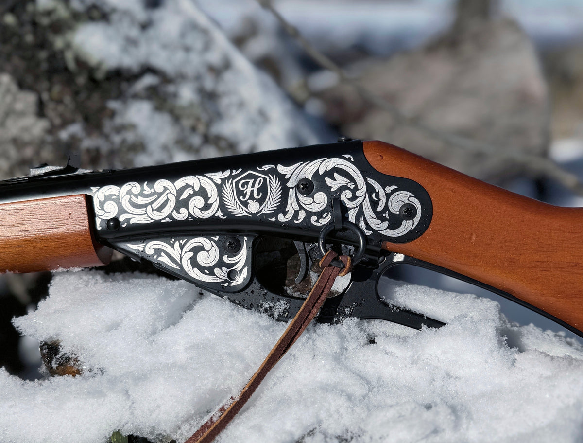 Decorative rifle stock with intricate white engraving on a snowy background