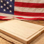 Wooden cutting board on a woven surface with an American flag in the background