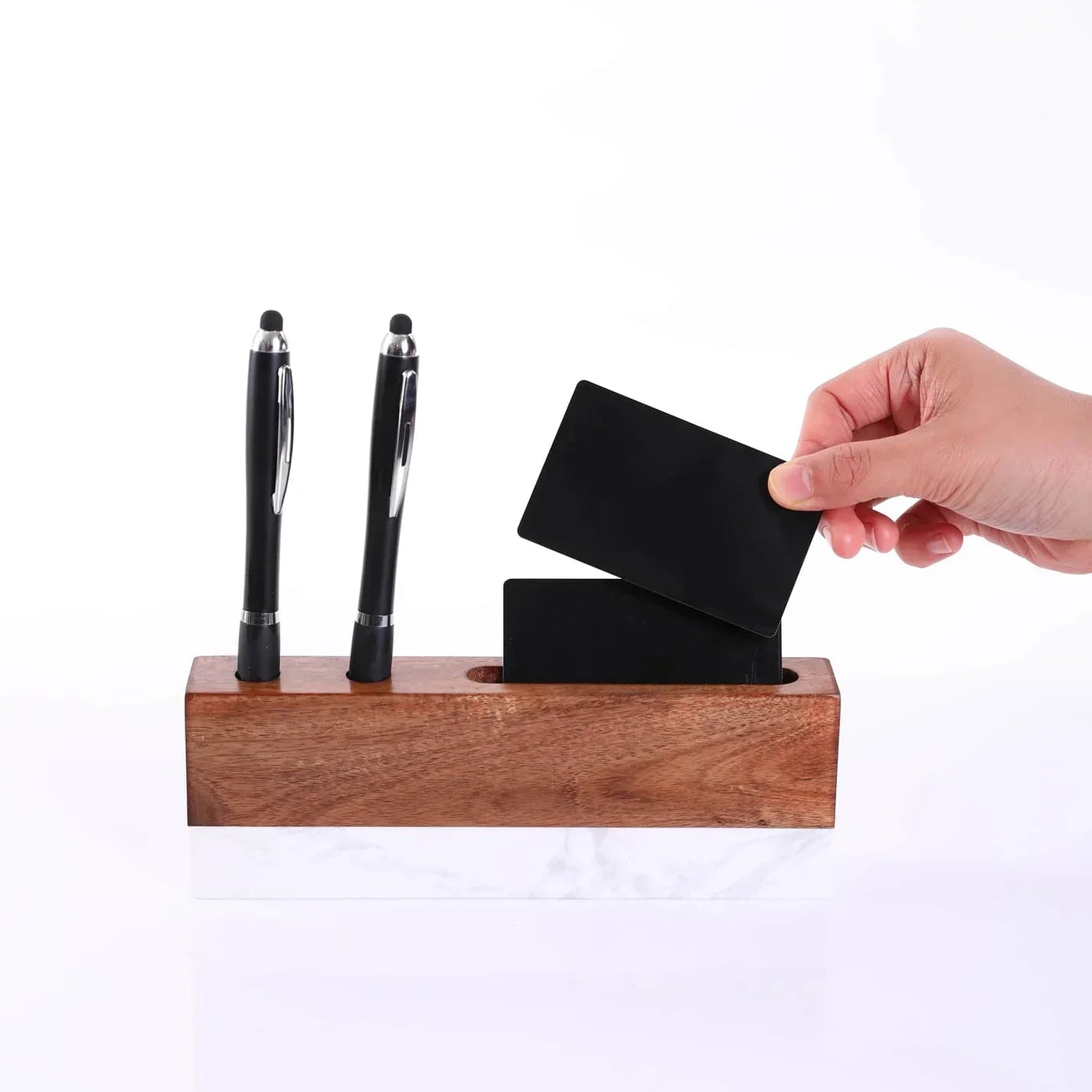 Wooden pen holder with two black pens and a black card, against a white background